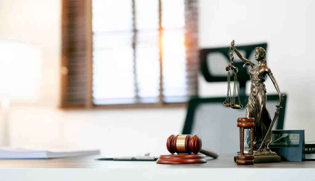 Estatua de la Justicia con una balanza y un mazo sobre un escritorio